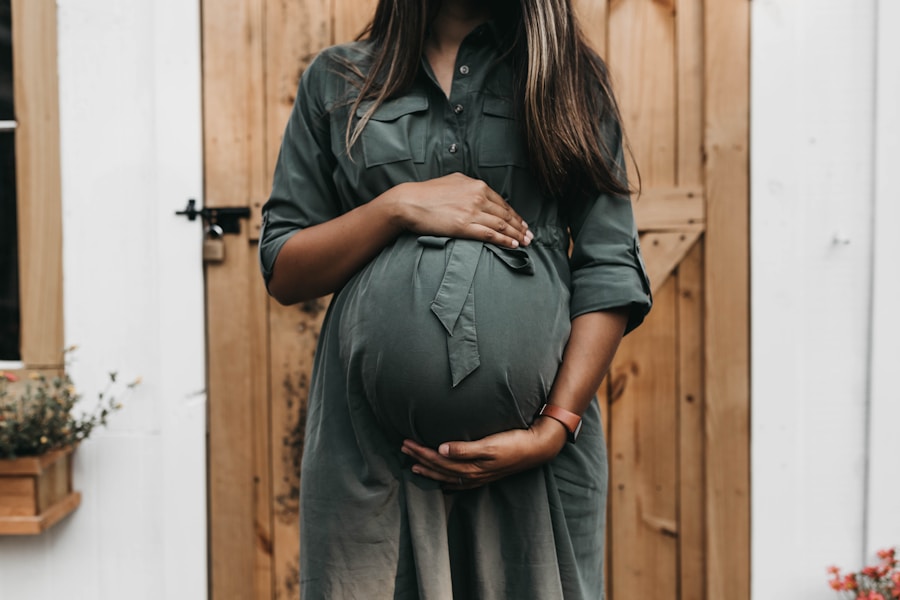 Pregnant woman in green dress, hugging belly