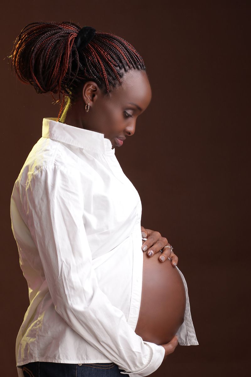 Pregnant woman in a white blouse, looking down at her belly